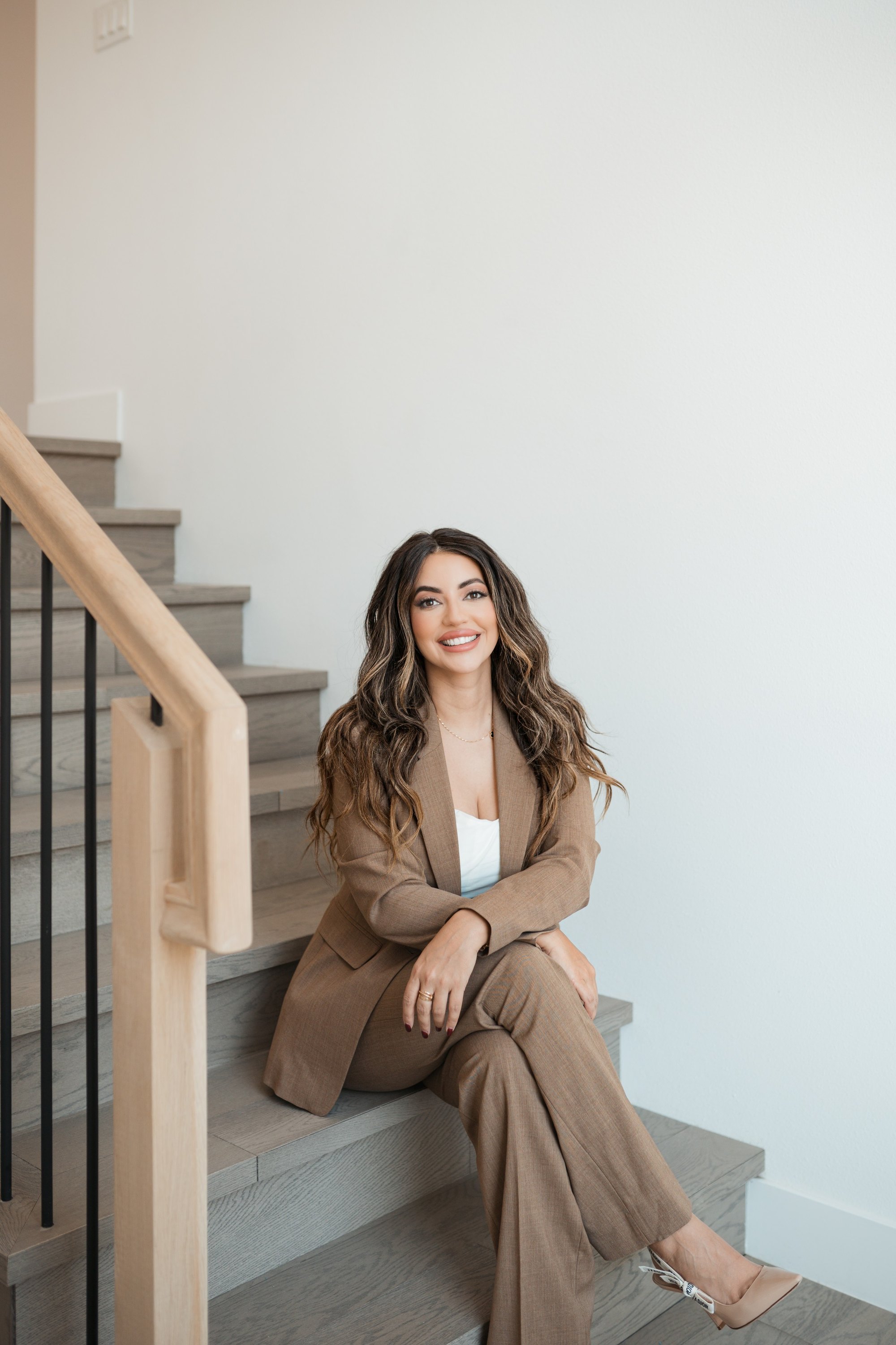 Sandra Ruelas seated on a staircase in a taupe suit