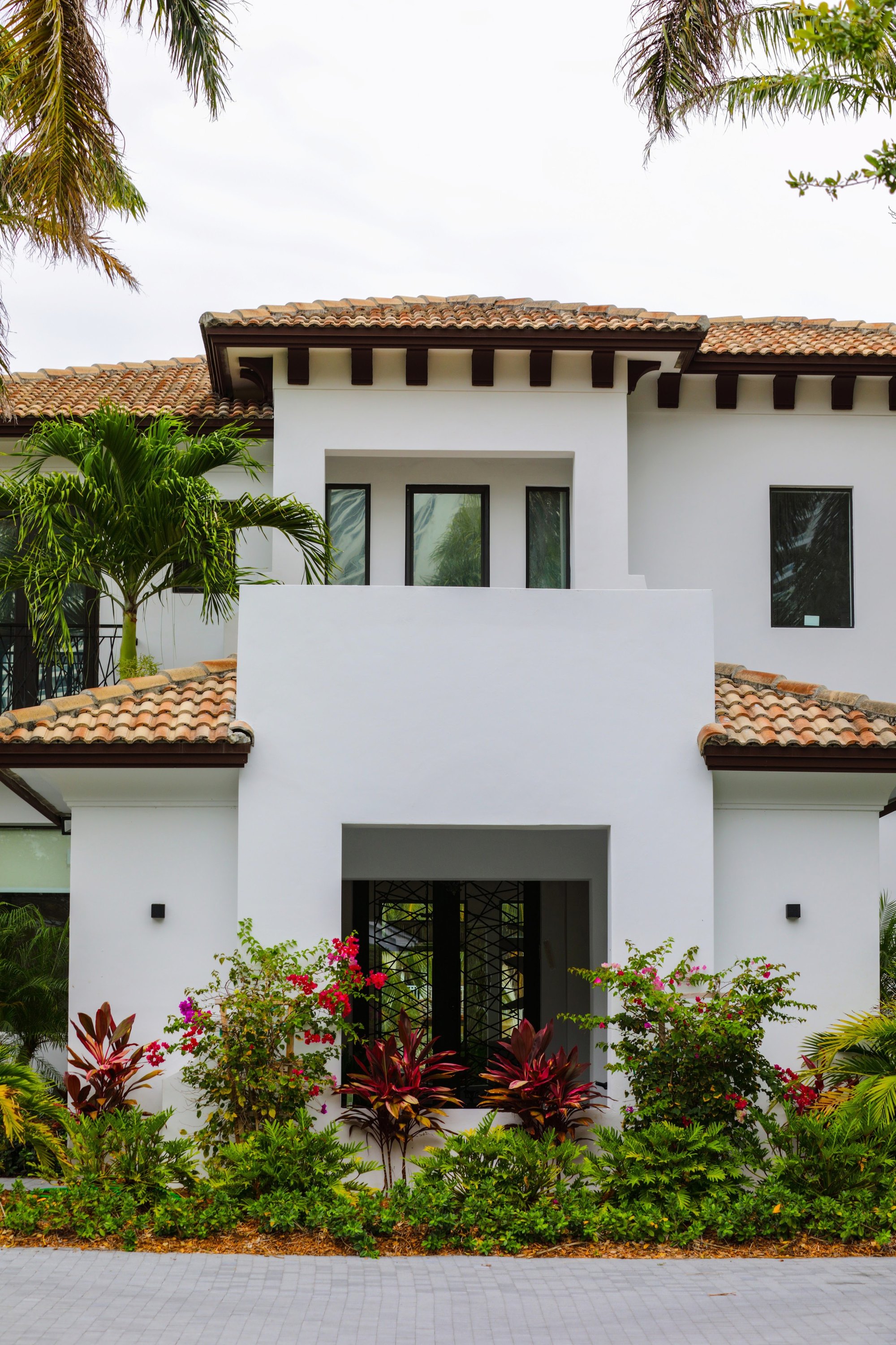 A white stucco home with tropical landscaping, illustrative