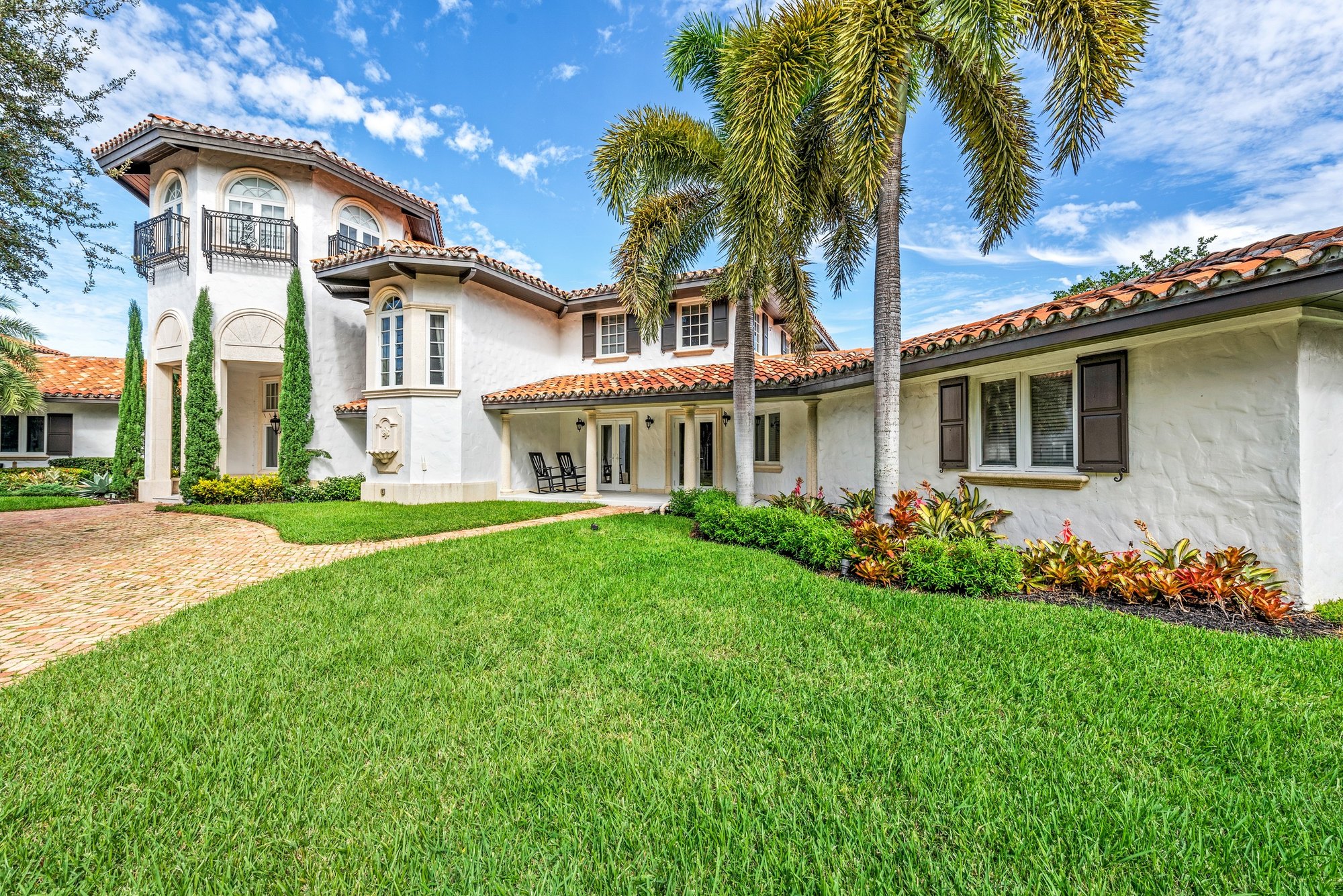 A white stucco home with tile roofs, illustrative